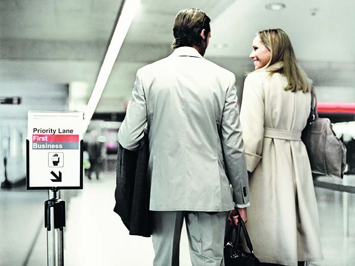 Ein Paar mit Handgepäck im Priority Lane am Flughafen