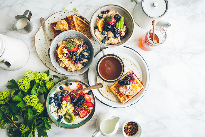 Lecker Brunch Teller mit Muesli, Waffeln, Kaffee, Honig und frischen Früchten 