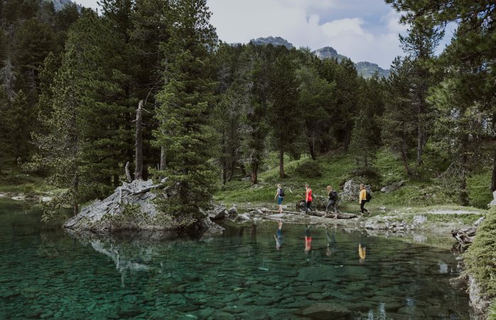 4 Leute wandern um einen Bergsee in der Schweiz