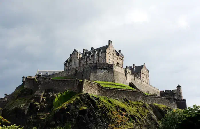 The historical landmark Edinburgh Castle, Scotland, set against a stormy sky.